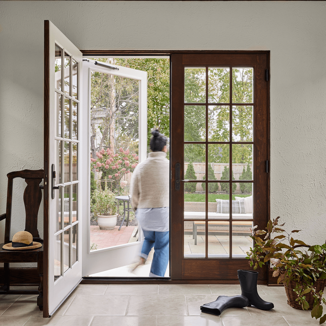 A woman walks out through an opened Marvin Ultimate Wood Swinging French door.